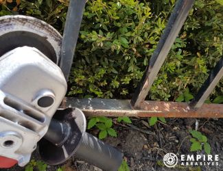 Using an angle grinder and grinding wheel to clean rust from a metal railing