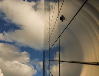 Metal sides of building with mirror finish reflecting the sky and clouds